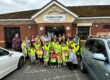 A group of litter pickers in high visibility vests A group of children and adults in yellow vests pose outside Jubilee Fields Community Centre.